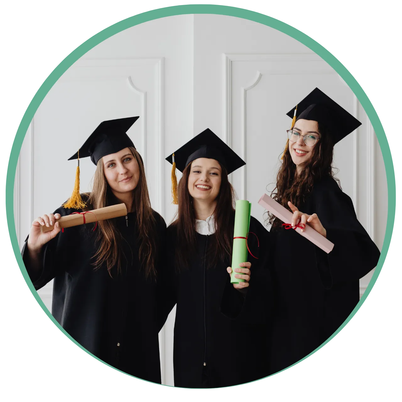 Three smiling female graduates in caps and gowns holding colorful diplomas.