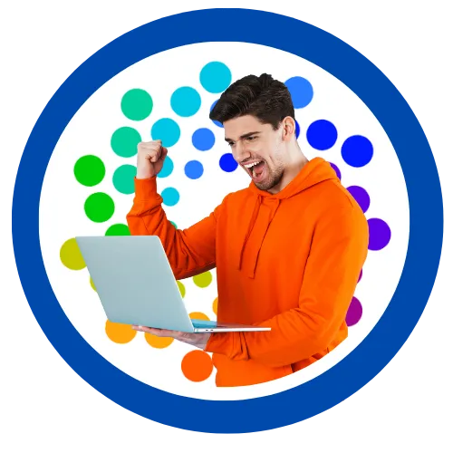 Excited young man in an orange hoodie holding a laptop and raising his fist in celebration.