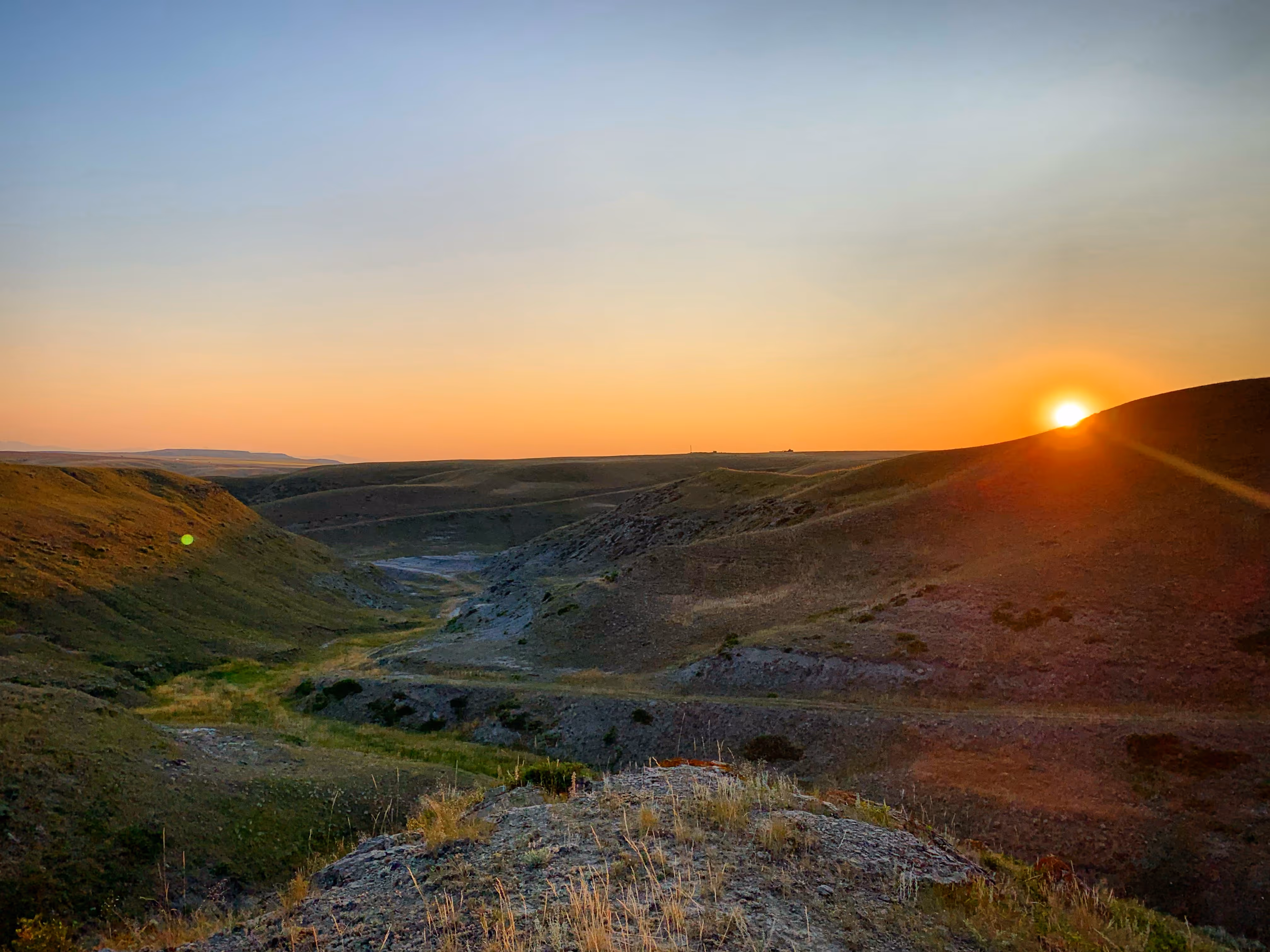 Panoramic view of rolling prairie hills at sunset