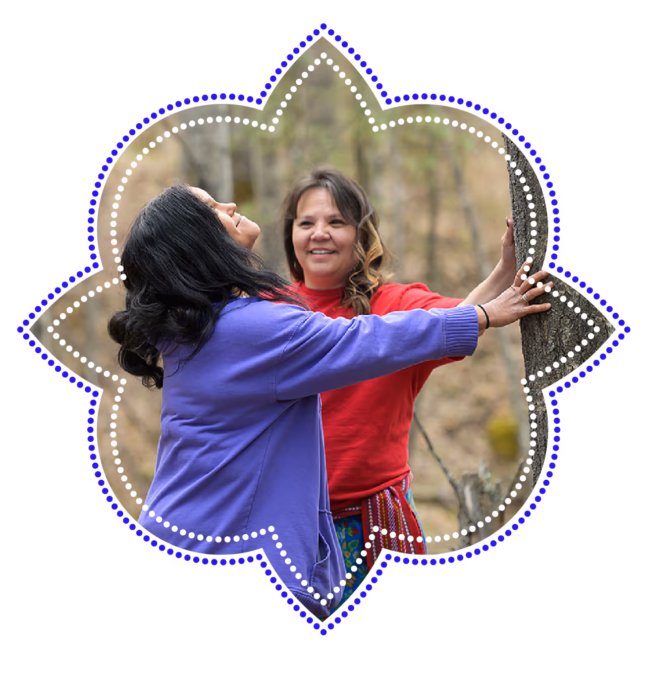Two indigenous women connecting with a tree in a forest during a land-based wellness activity
