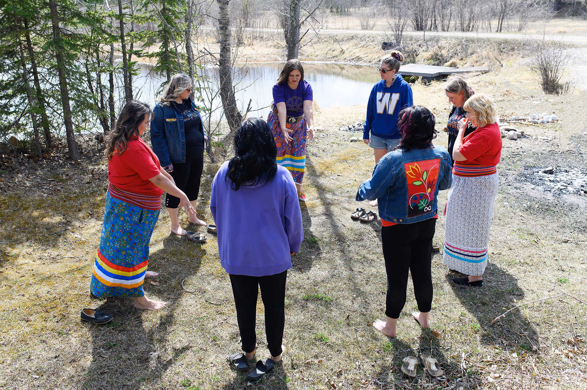 Group standing in a circle during a guided outdoor cultural wellness activity near a river