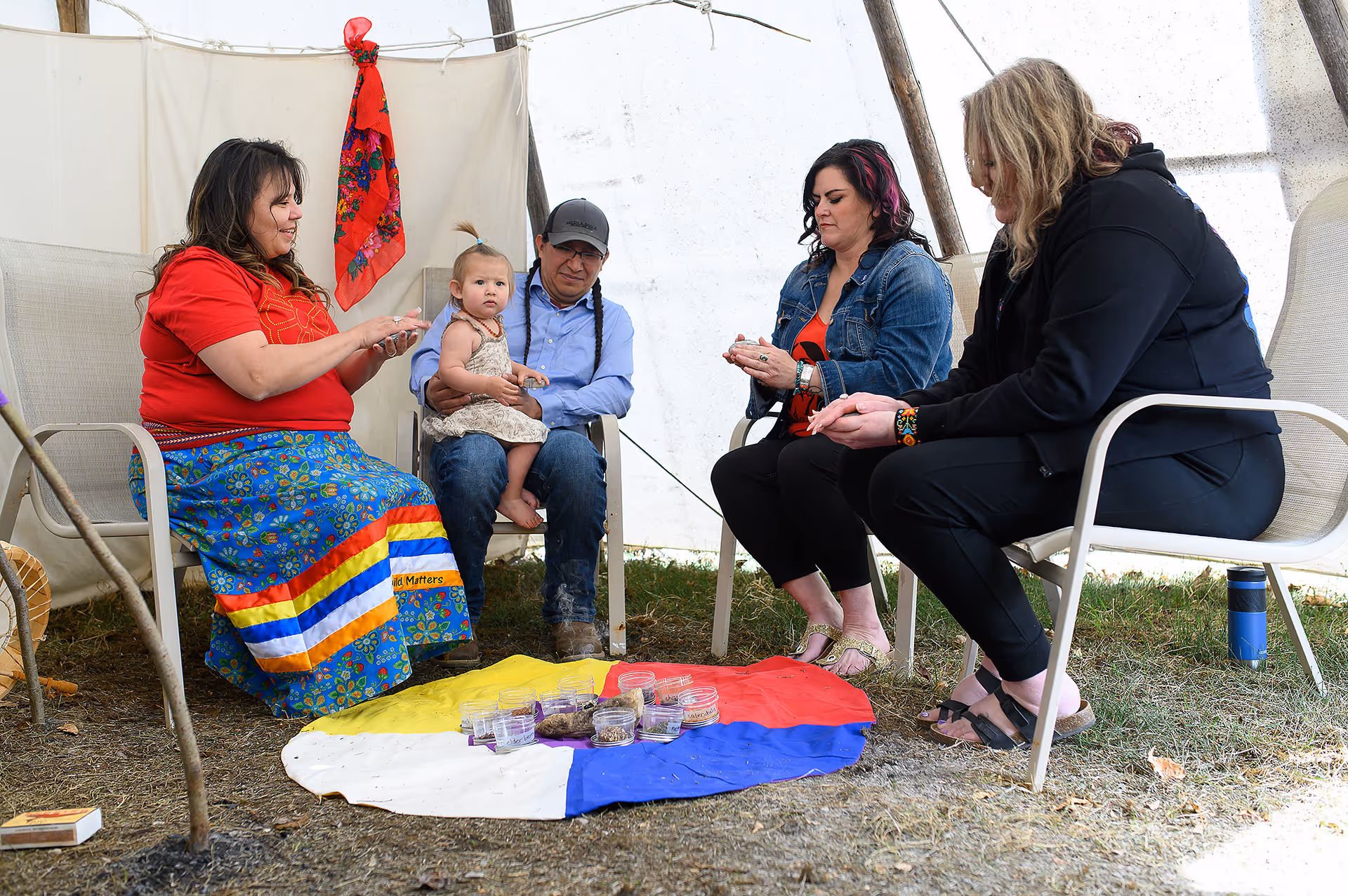 Facilitator leading a small group wellness circle inside a traditional teepee during a cultural learning activity