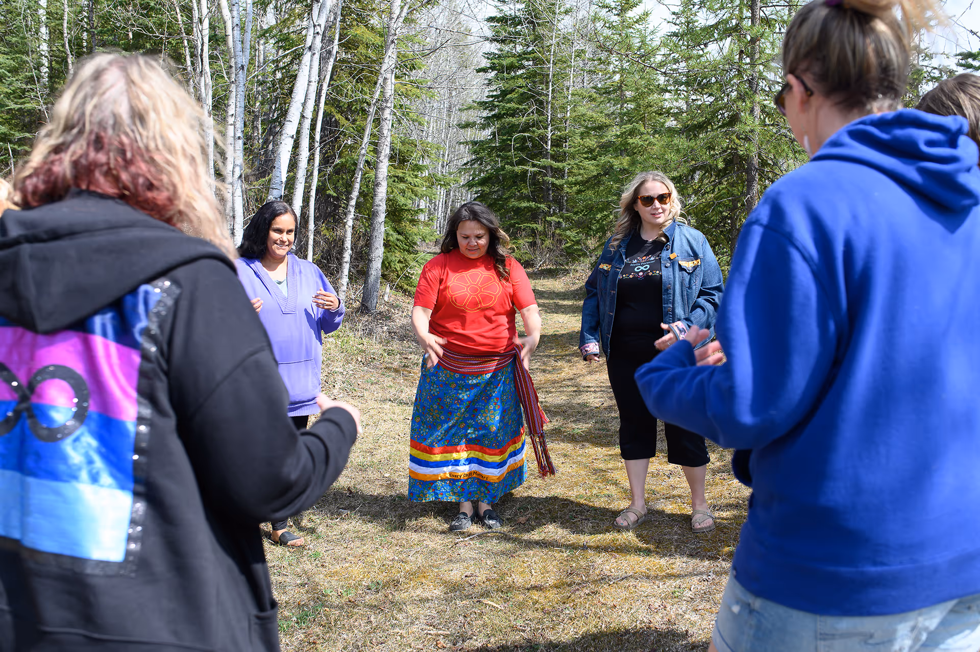 Group participating in a guided outdoor cultural wellness activity in a forest setting