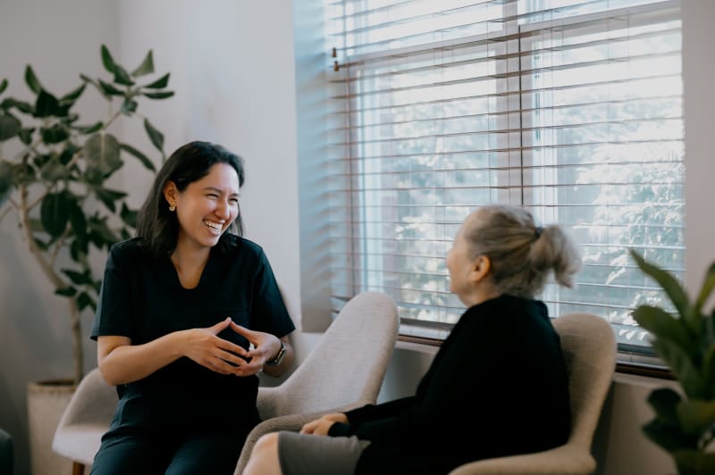 Female dentist speaking with mature patient in modern office consultation room