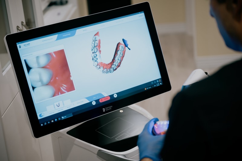 Dental professional reviewing 3D scan images on computer monitor with patient