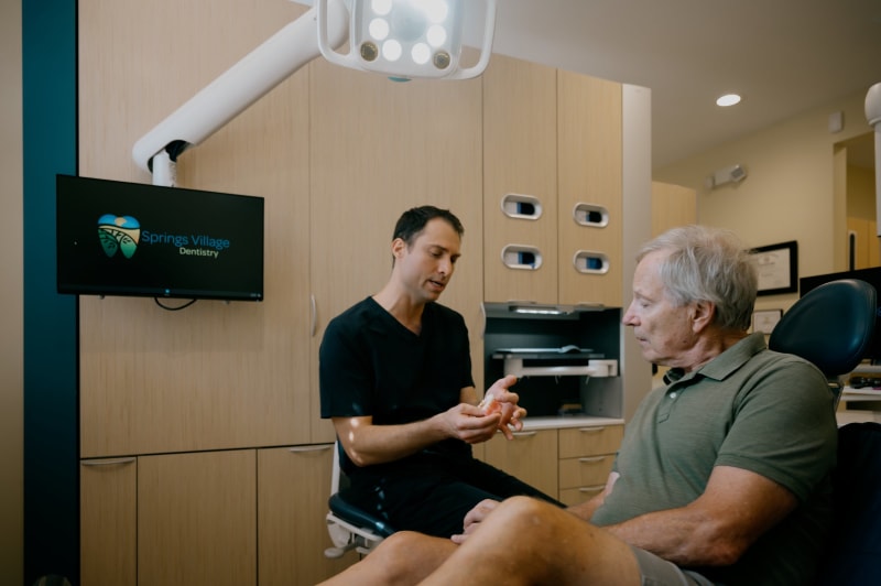 Dentist performing hands-on jaw/facial examination on male patient in clinical setting