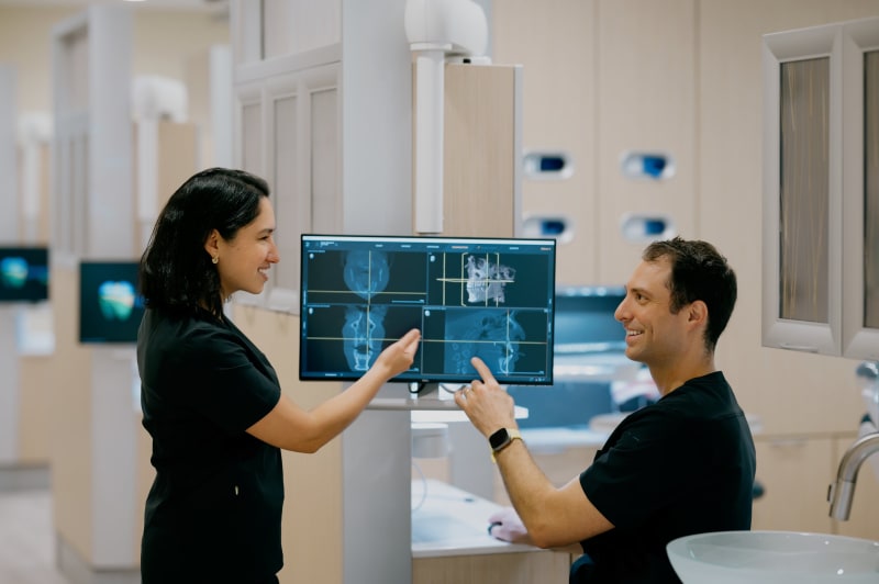 Two dental professionals reviewing X-ray images on computer screen together