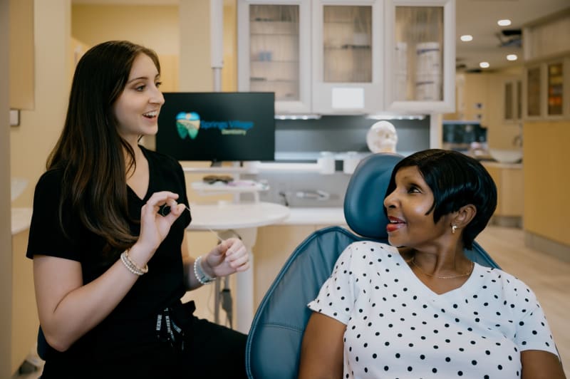 Dentist speaking with and examining a patient in clinical treatment room