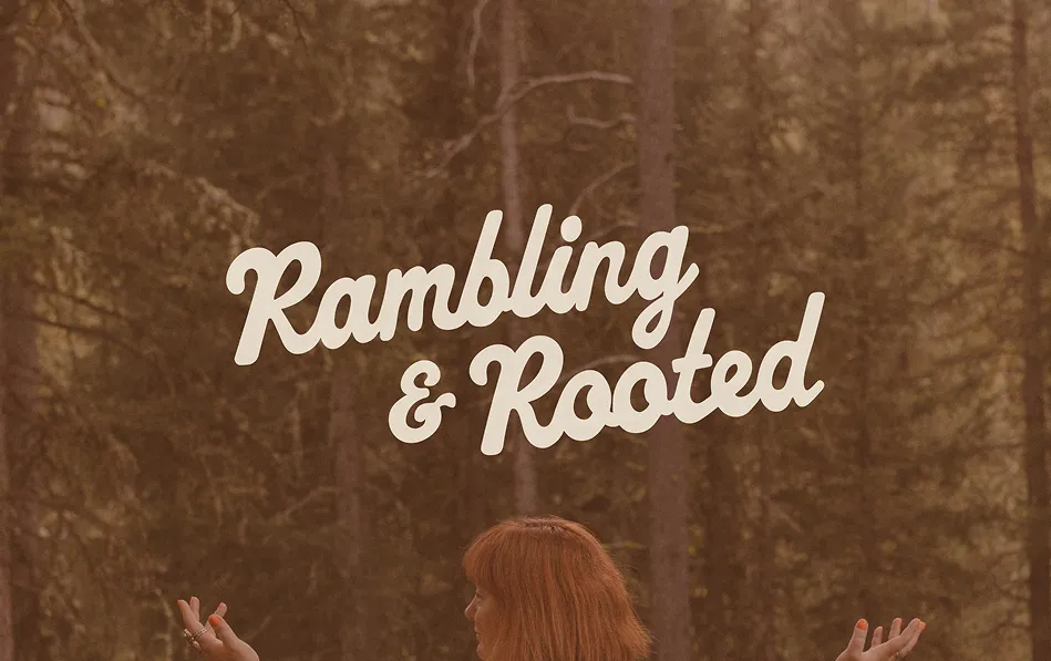 Person with red hair standing in a forest with arms outstretched beneath the words 'Rambling & Rooted'.
