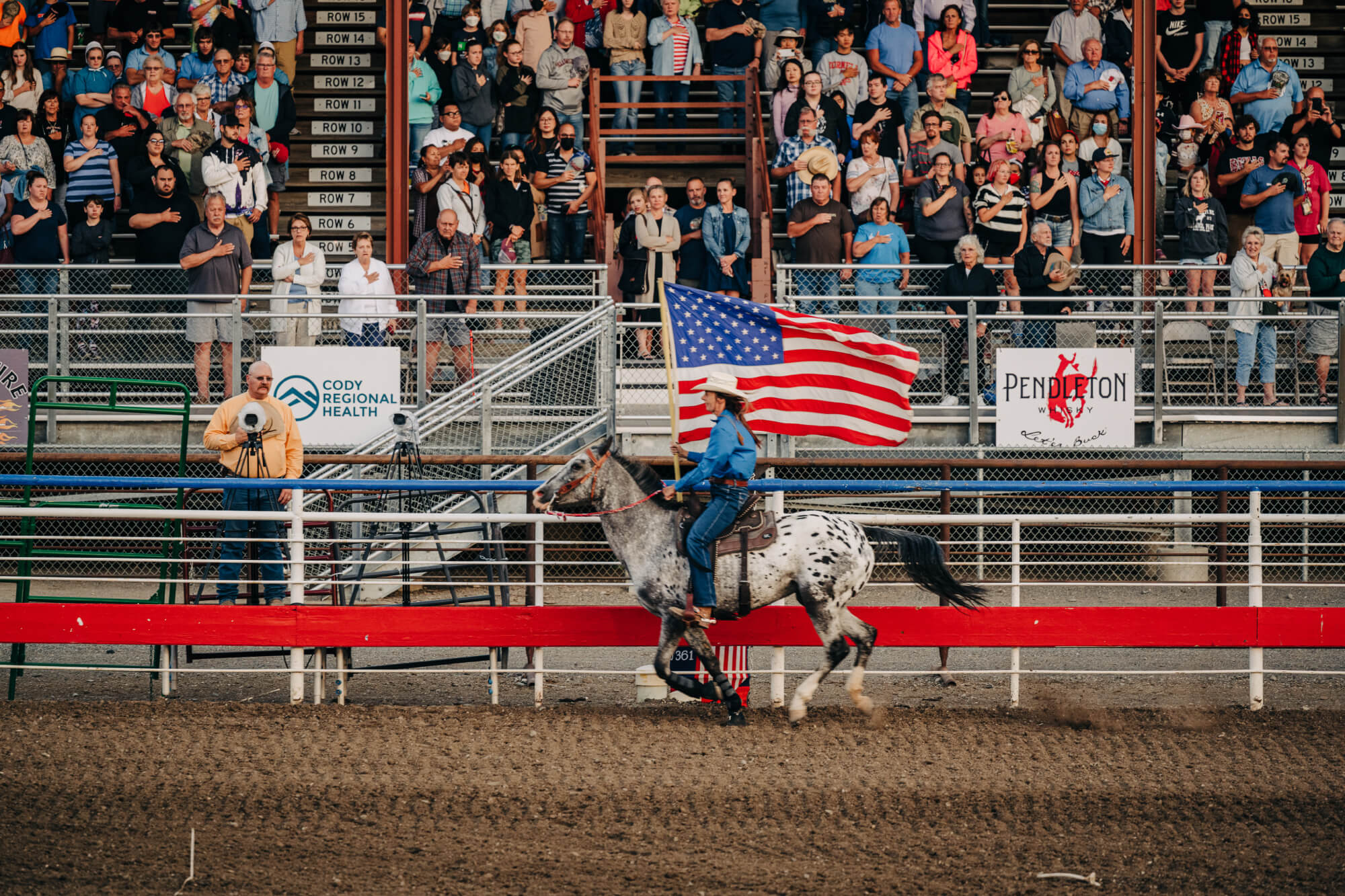 Horse rider with American flag riding around rodeo