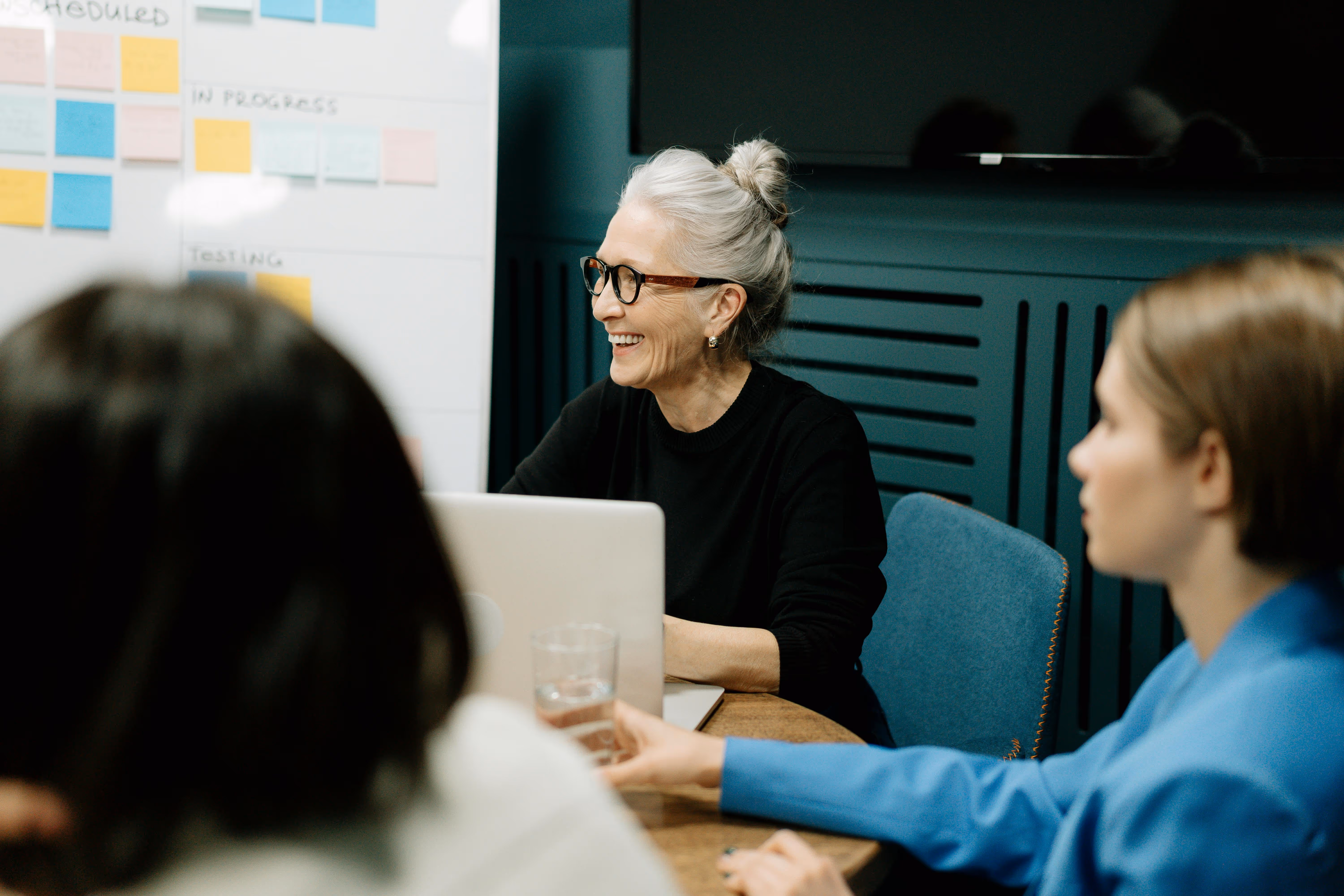 older woman talking with others at desk