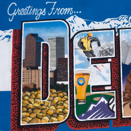 Colorful mural reading 'Greetings From Denver' with letters filled with local imagery including skyscrapers, skiing, beer, and the Rocky Mountains.
