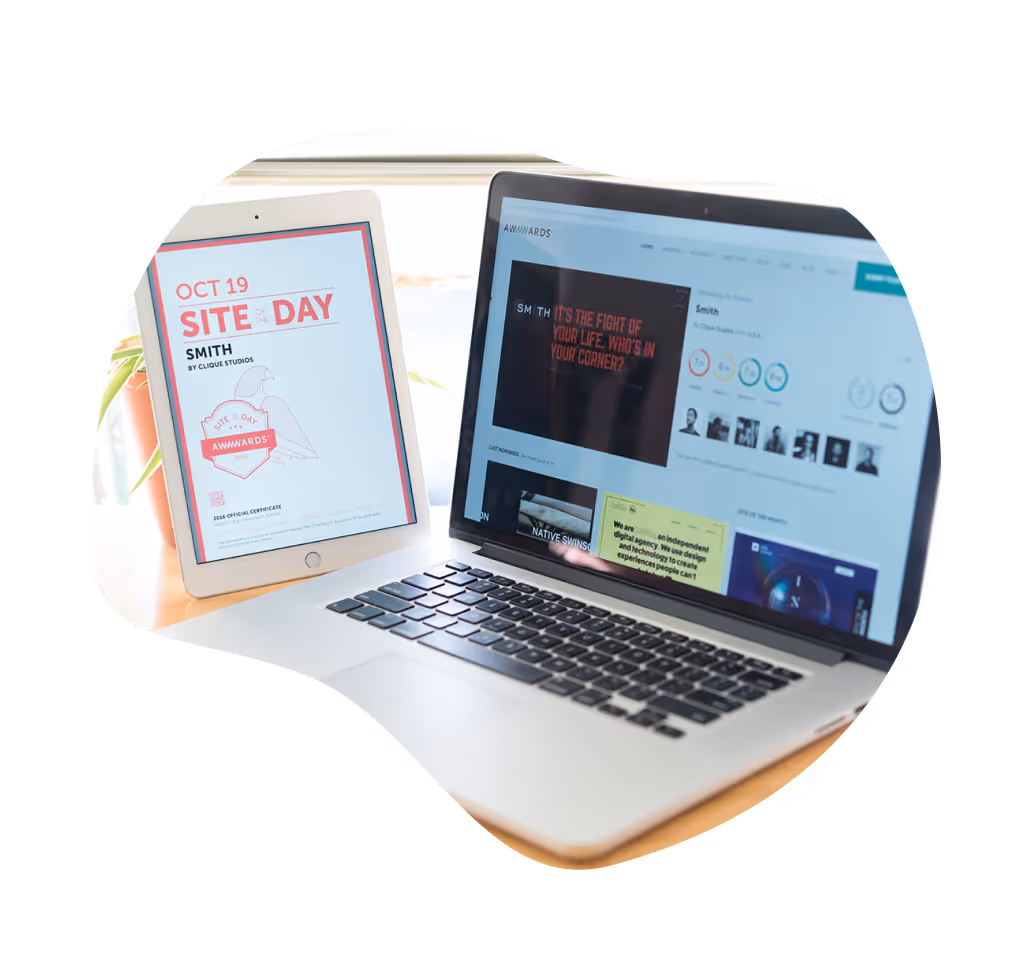A laptop and an iPad displaying a Site of the Day award from Awwwards