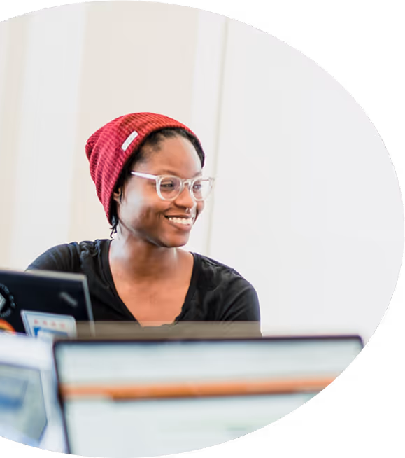 A smiling person sitting behind a laptop