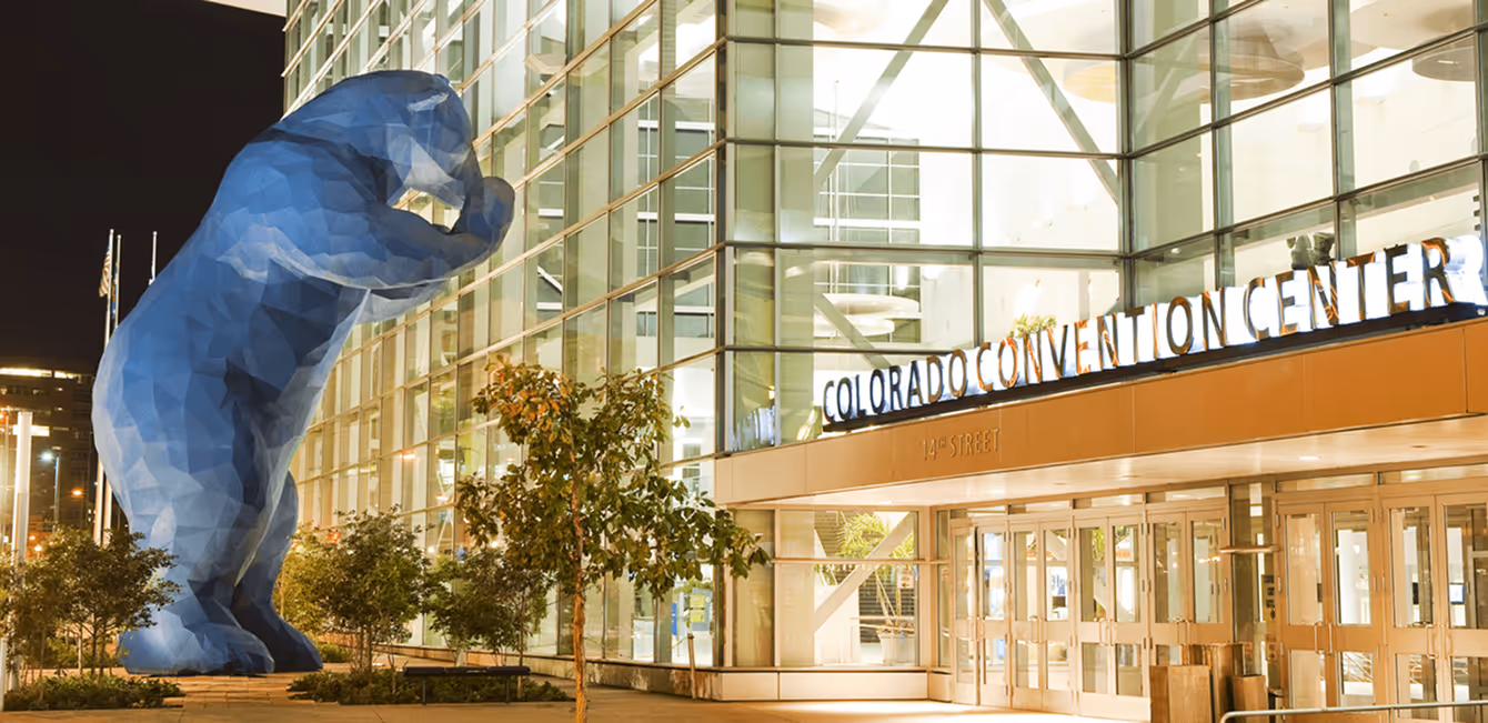 Iconic giant blue bear sculpture peering into the Colorado Convention Center windows at night.