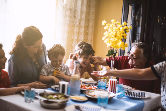 A multigenerational family sharing a joyful meal around a dining table with food and drinks