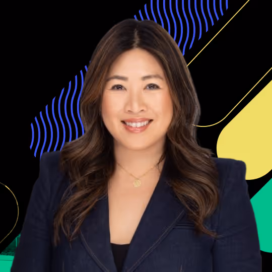 Smiling woman with long wavy hair in a navy blazer, against a colorful geometric background.
