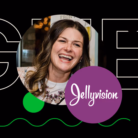 Smiling woman with wavy brown hair in a white top and floral necklace, next to a purple logo with the word 'Jellyvision' on black background.