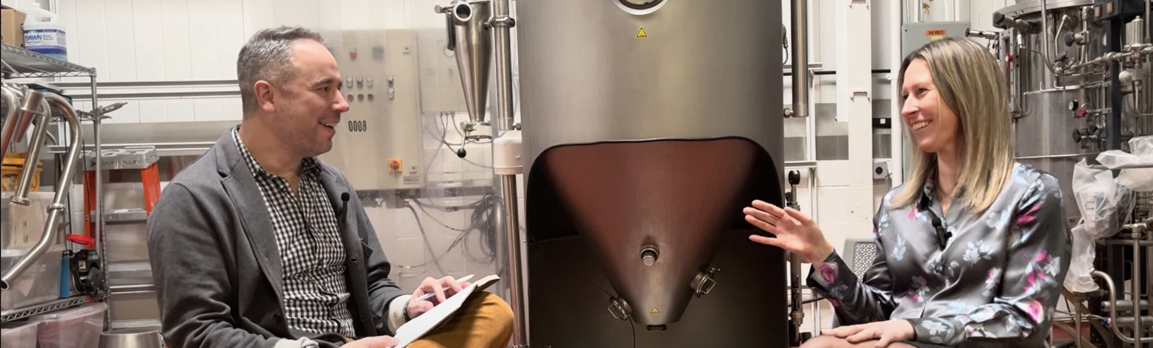 Ted Novak interviews Julie Drainville of Edlong Flavor Solutions beside mixing equipment on the Ted Listens podcast
