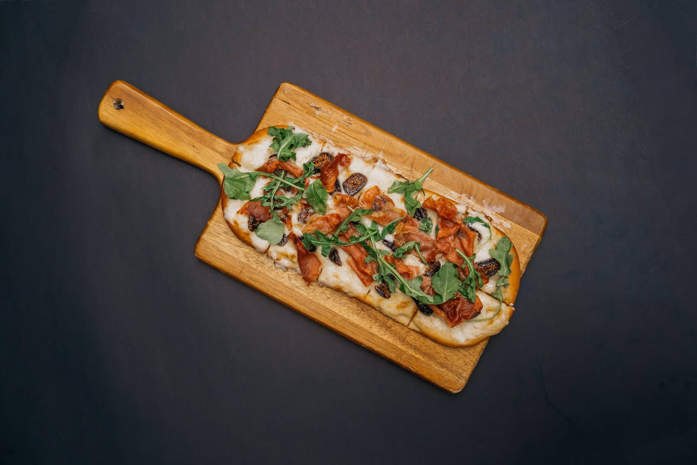 A wooden cutting board with a pizza on it.
