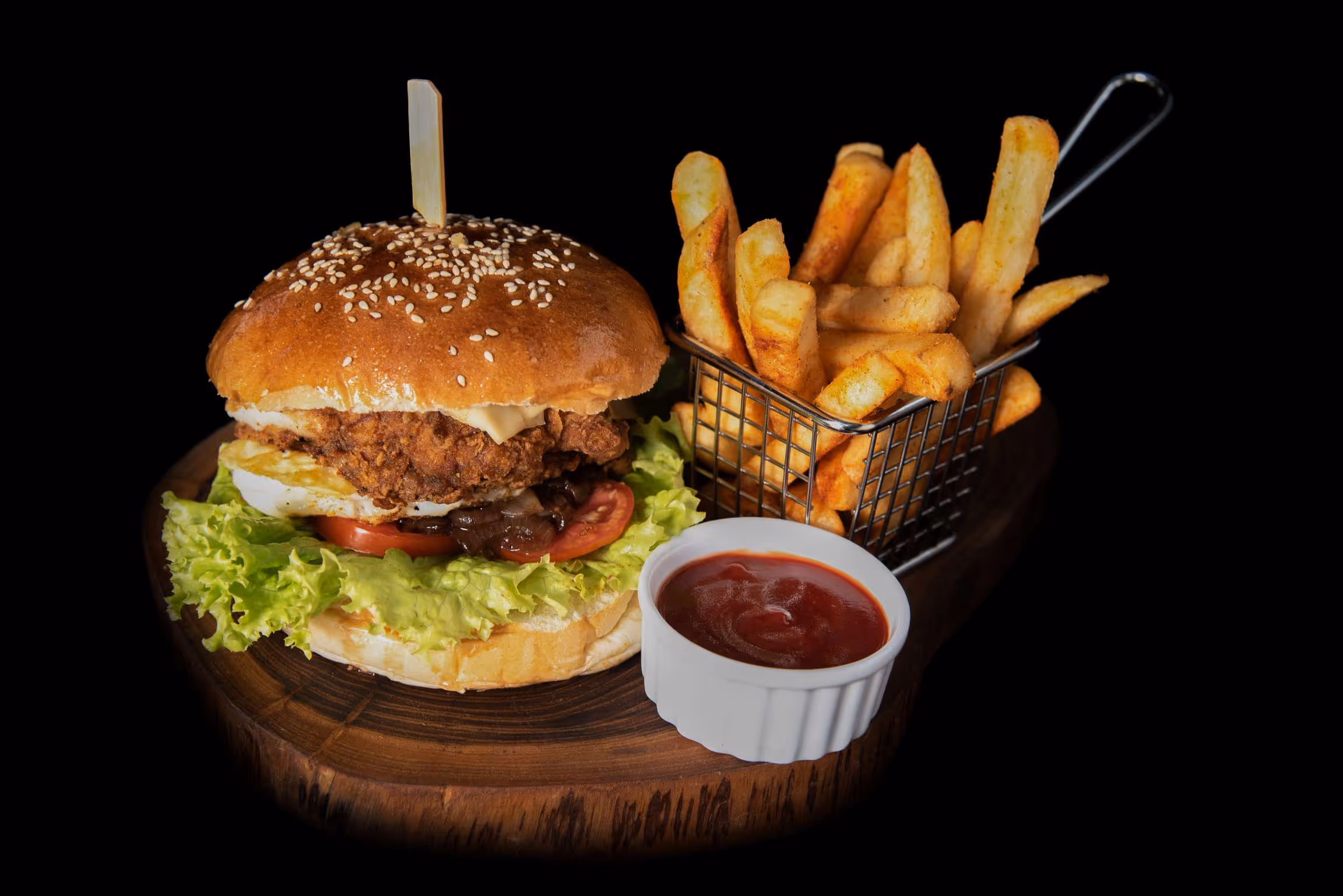 A burger with fries and ketchup on a wooden tray.