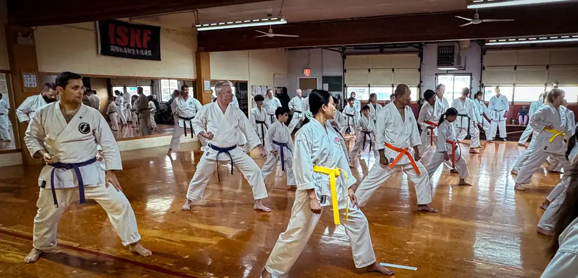 Students performing synchronized karate techniques during the December 13, 2025 belt grading test at Port Moody Shotokan Karate Club, under the ISKF banner in the traditional dojo.
