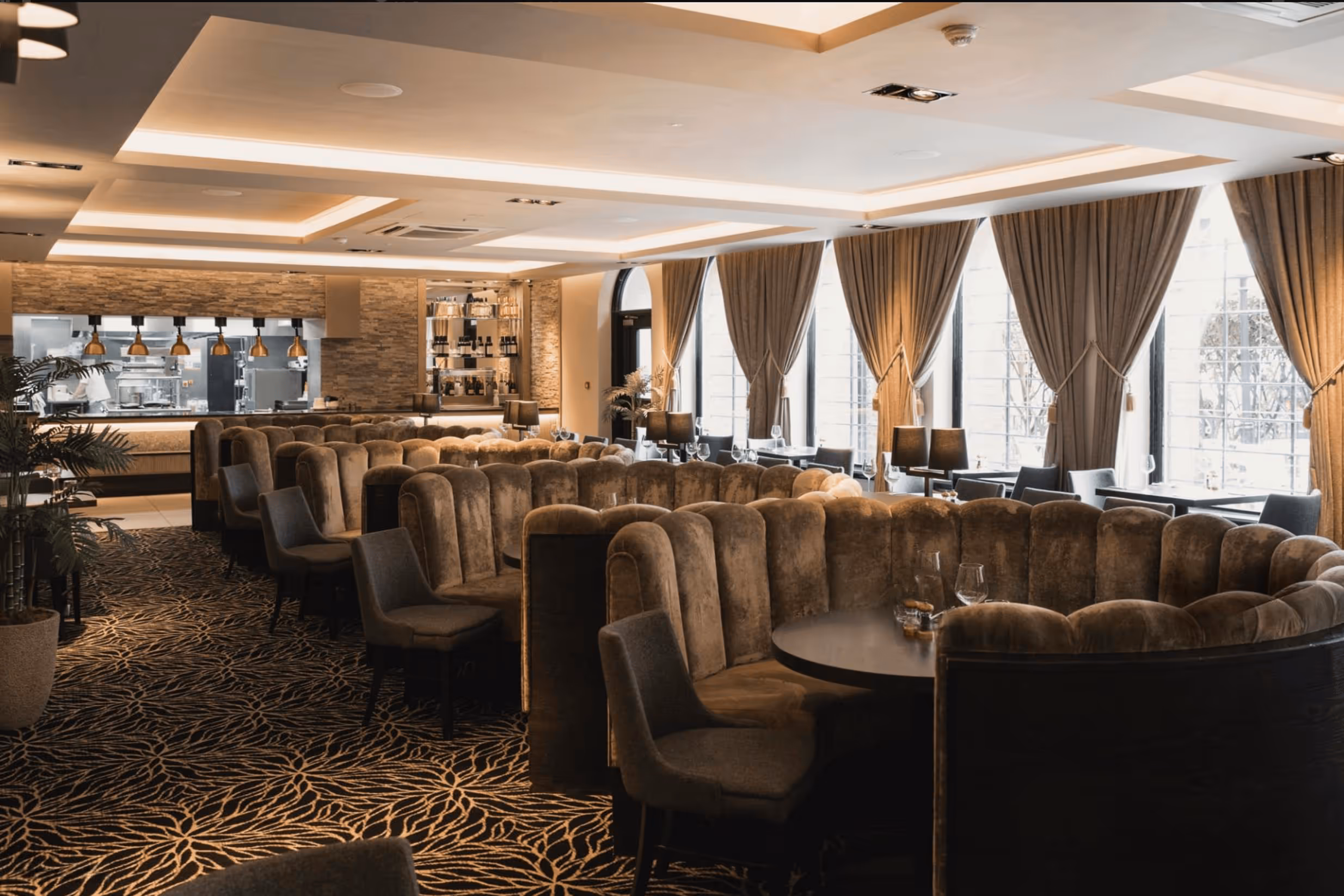 Elegant restaurant interior with plush seating and open kitchen.