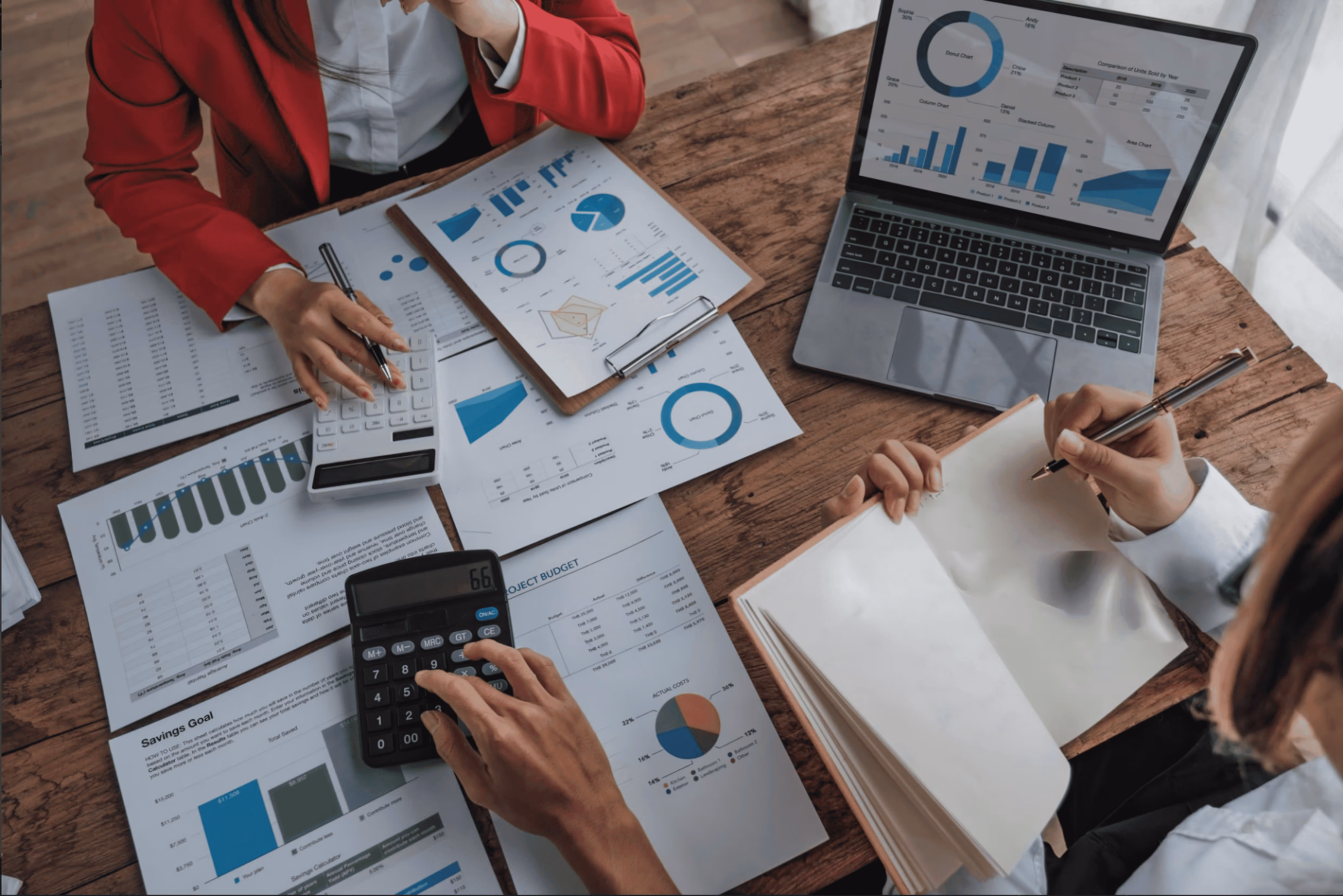 People working with charts, calculators, and laptop on financial reports.