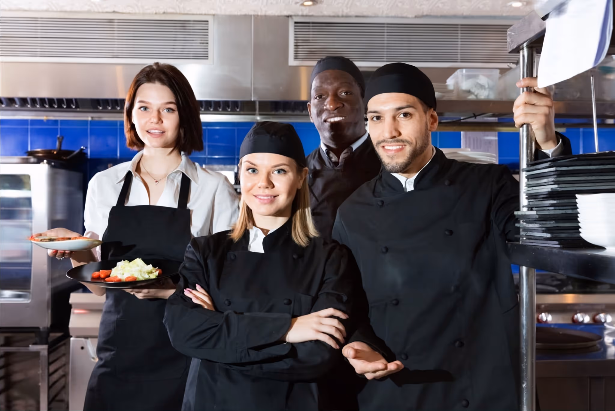 Group of chefs and staff in a restaurant kitchen.