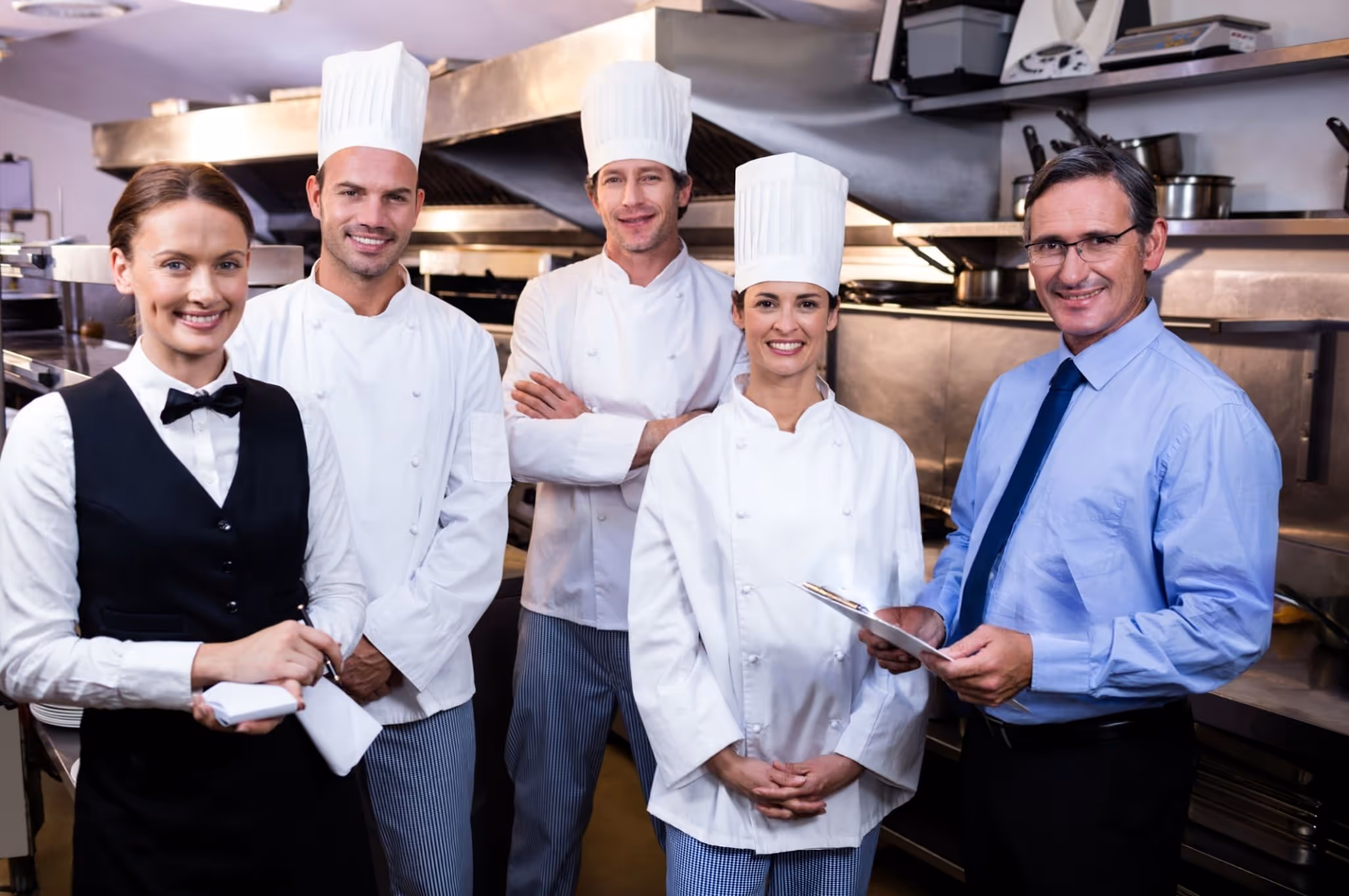 Restaurant staff and chefs smiling in the kitchen.