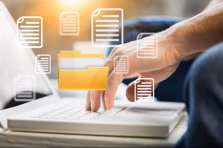 Hand typing on a laptop keyboard with floating icons of documents and a yellow folder representing digital file management.