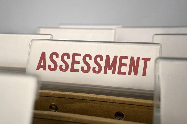Close-up of a file folder tab labeled 'ASSESSMENT' among other plain white tabs.