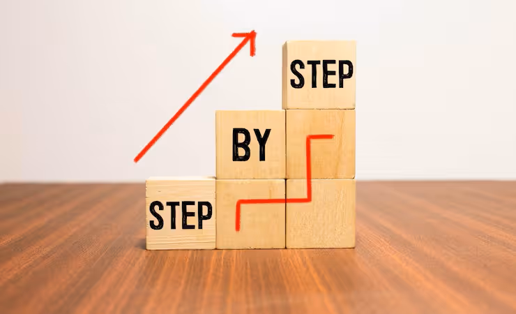 Wooden blocks stacked like stairs with words 'STEP BY STEP' and a red upward arrow above.