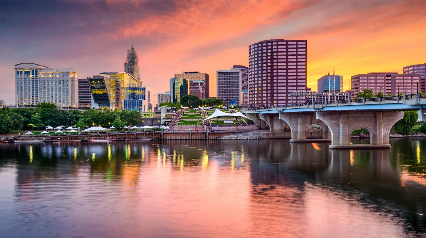 Photo of the Hartford, Connecticut, city skyline reflecting in the water at sunset, representing a key US market for homeowners to sell their house and access home equity