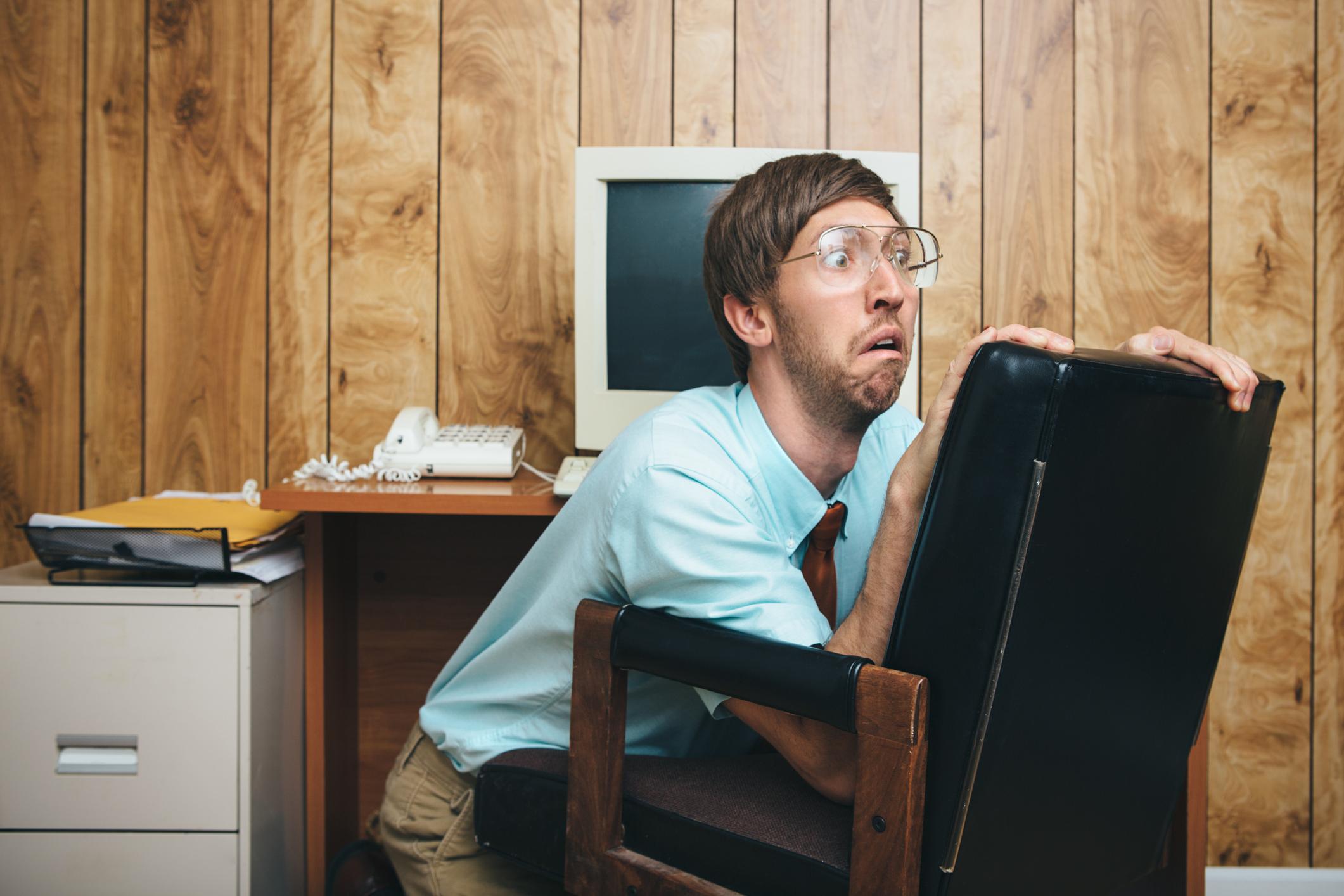 Man ducking behind office chair