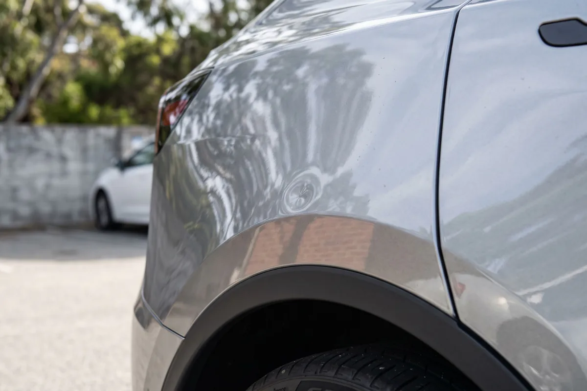 Dent in the rear quarter panel of a silver car above the wheel arch