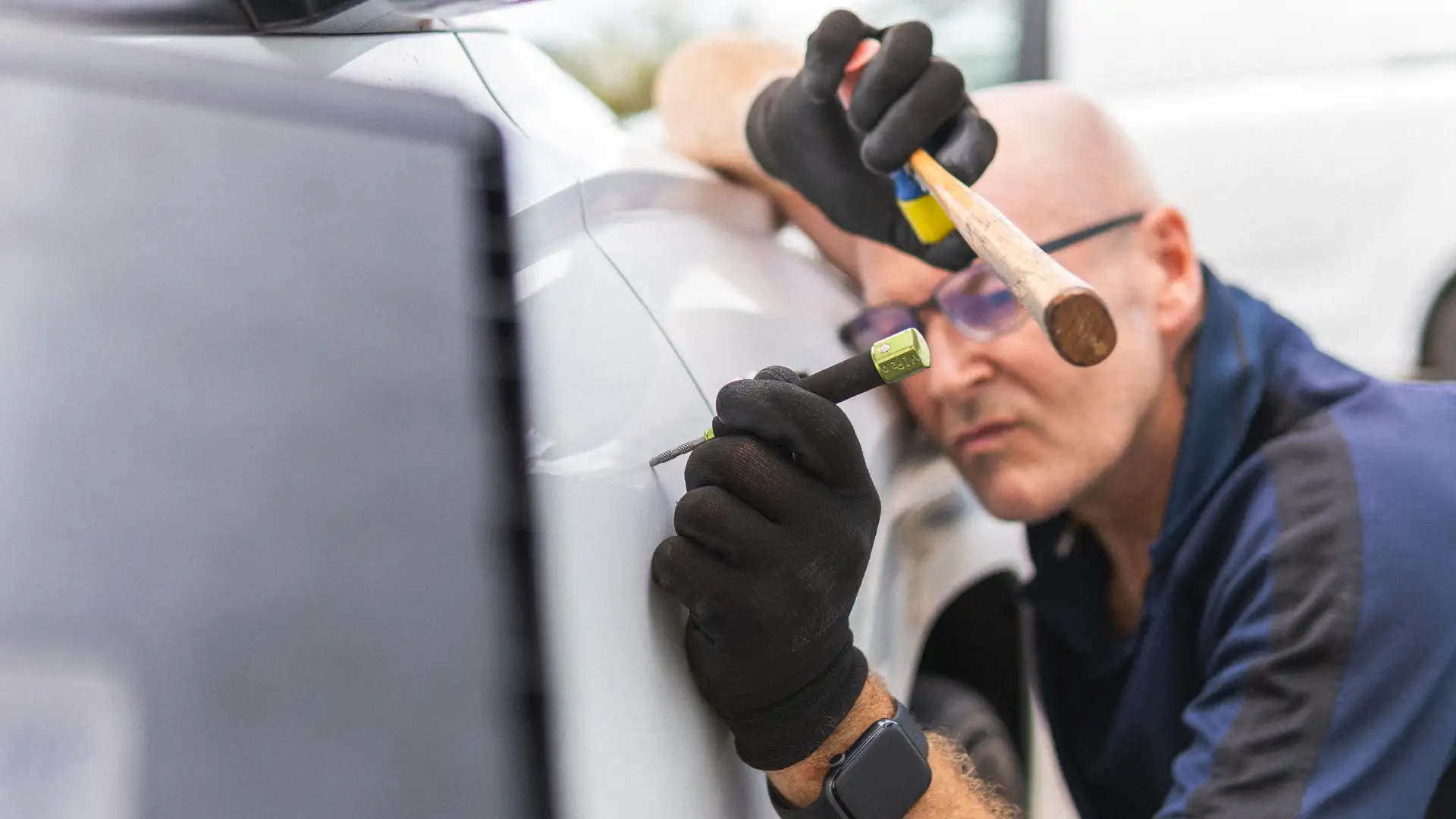 Impact Dents technician using a hammer and knockdown tool on a car panel during paintless dent repair in Perth