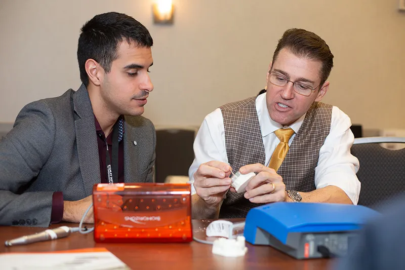 Two professionals discussing work with various equipment on table