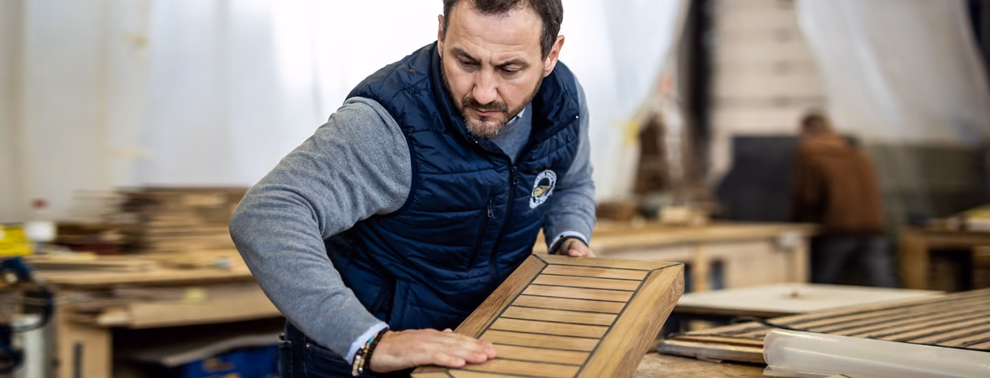 Teak deck panel with inlaid seams being checked by hand in the Galeon workshop.