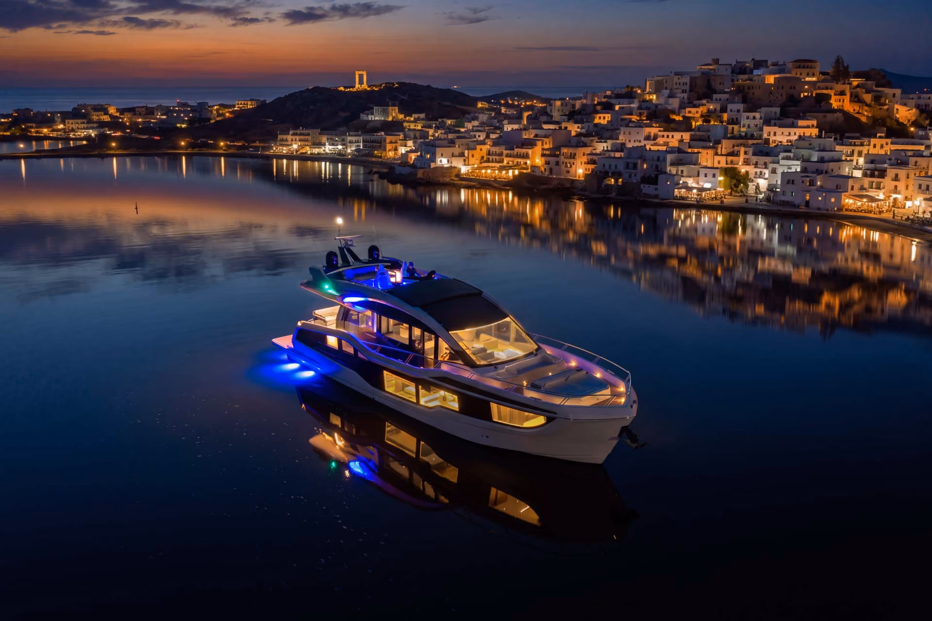 Aerial view of the Galeon 570 SKY lit at night in a calm bay.