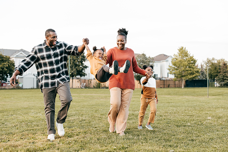 Family walking, with parents playfully swinging child between them.