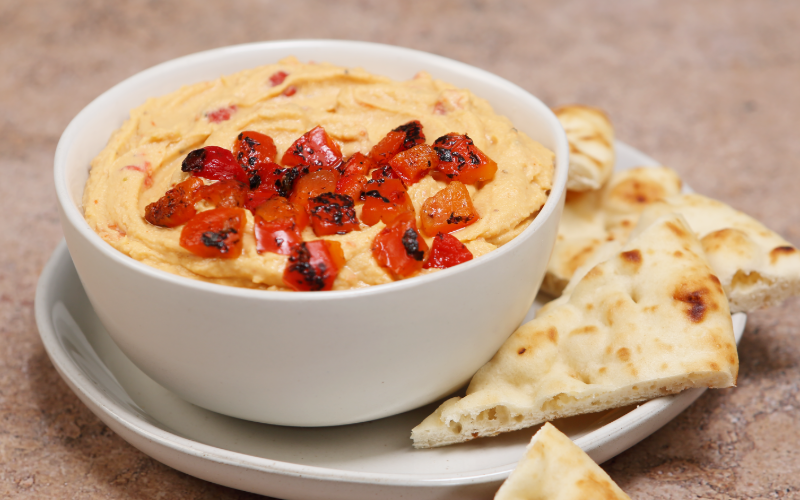 Creamy roasted red pepper dip topped with fire-roasted pepper pieces and served with flatbread.