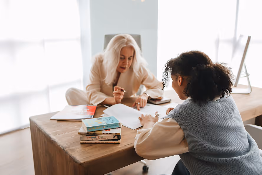 a student sitting down at a table studying with a tutor