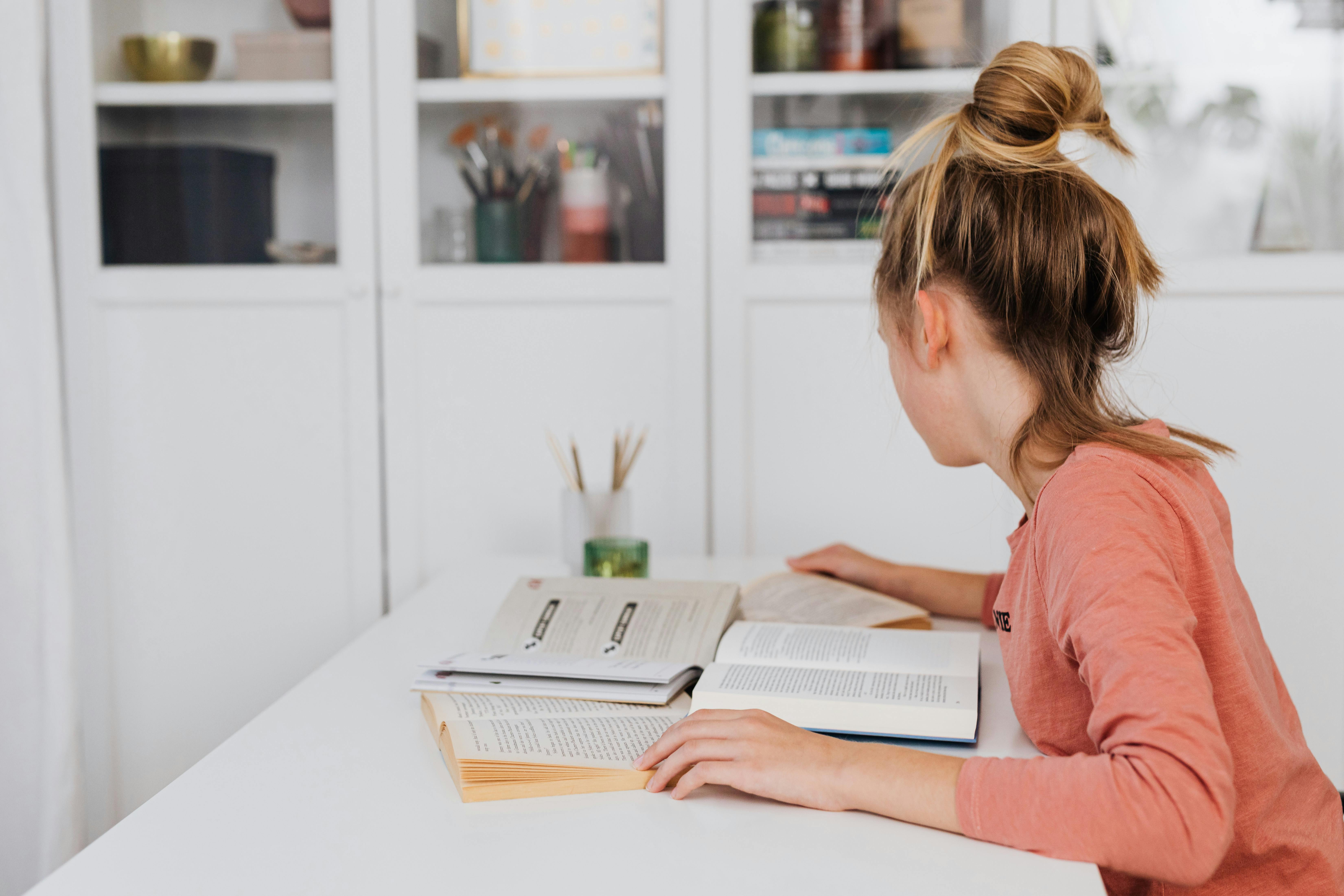 a student studies at a desk with several books