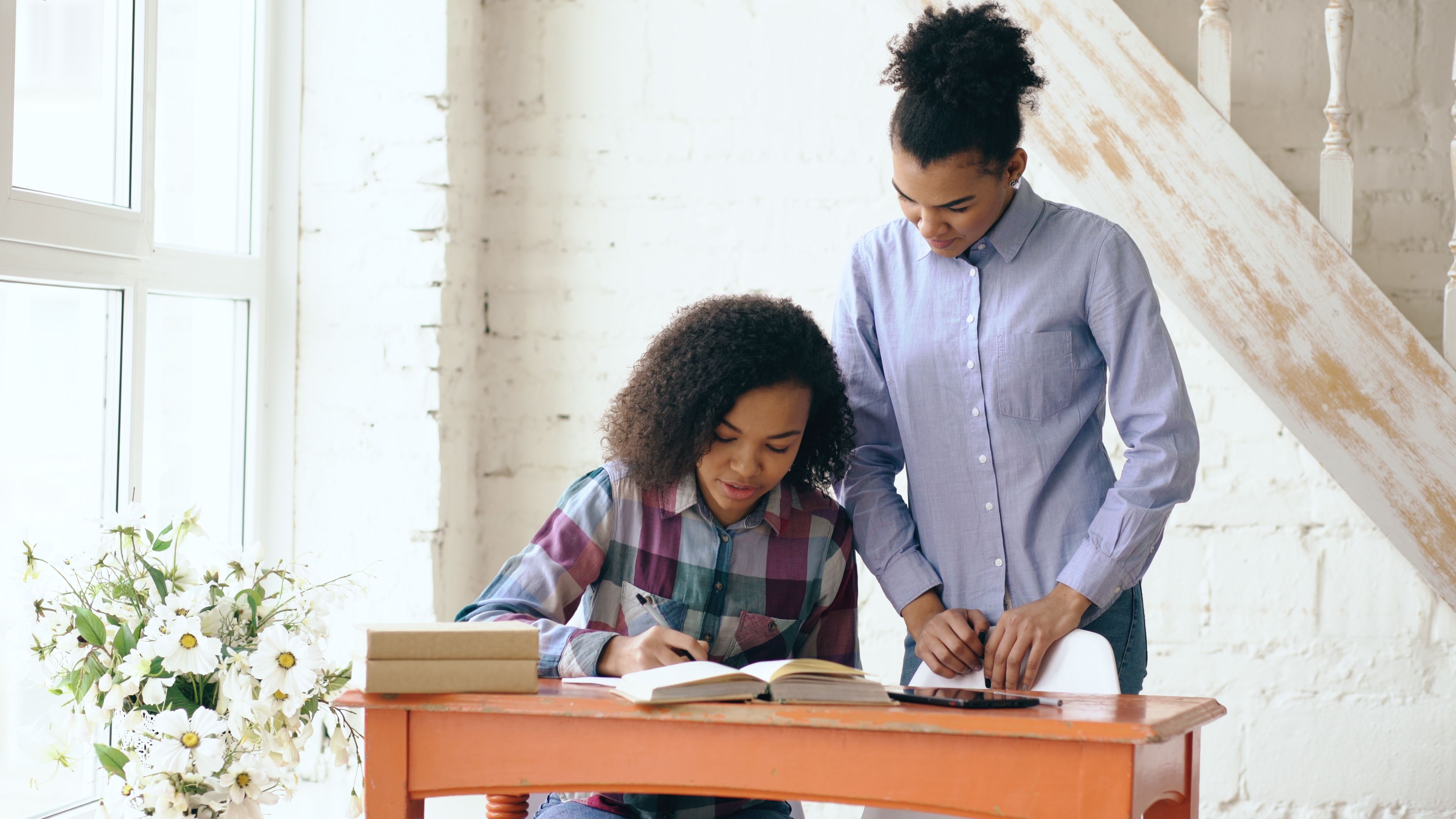 "Parent watching a teenage student study at a home desk, representing when to step in and support schoolwork.