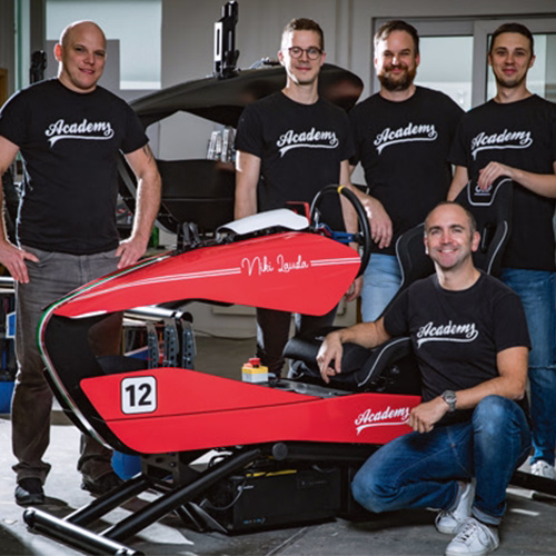 Teamfoto der Mechaniker und des Teams rund im einen roten Ferrari-Simulator