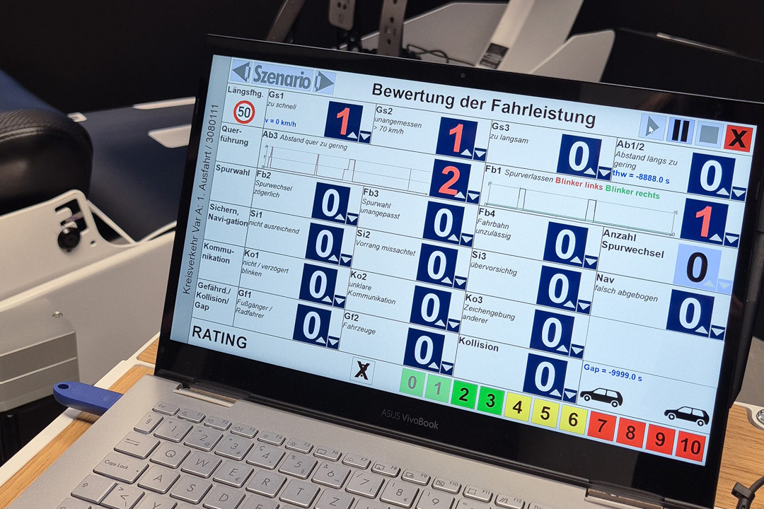 Laptop zeigt Bewertung der Fahrleistung mit numerischen Bewertungen und Farbcodierung in Deutsch.