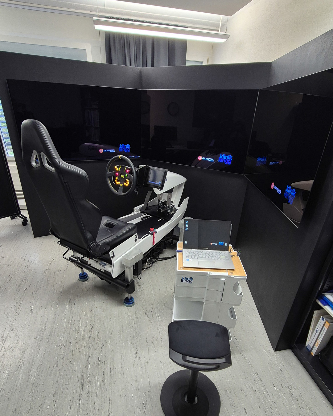 Appareil de simulation avec siège, volant et trois écrans pour la simulation de conduite à la clinique Lengg.