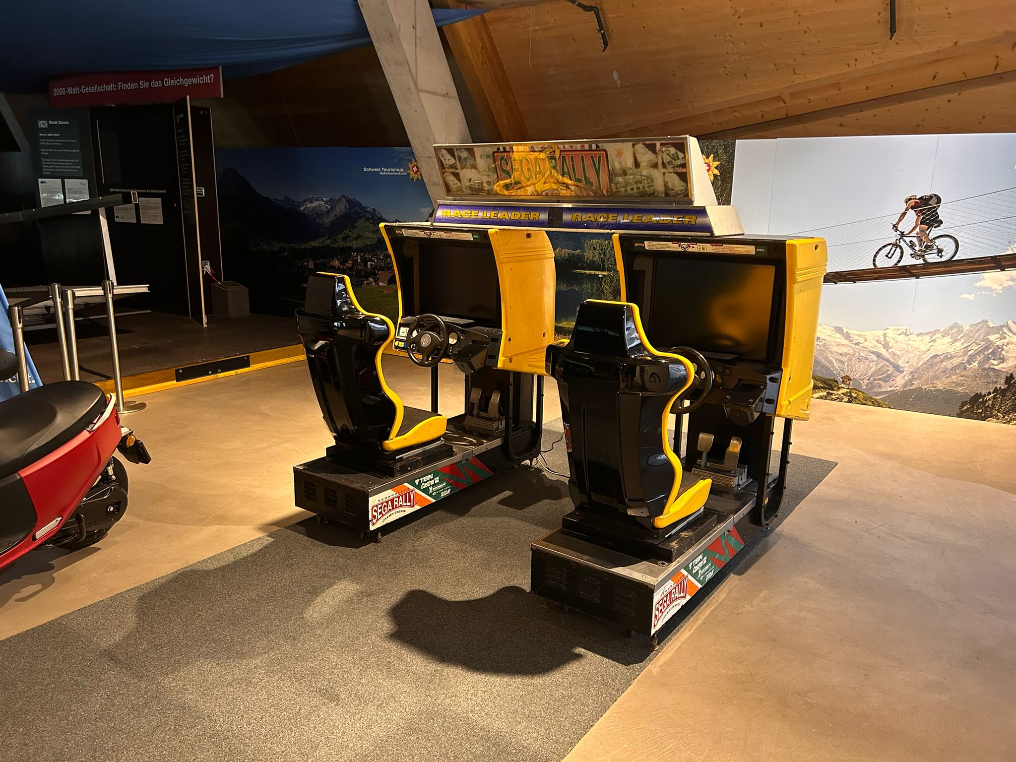 Zwei gelb-schwarze Sega Rally Arcade-Rennspiel-Simulatoren mit Sitzen und Lenkrädern.