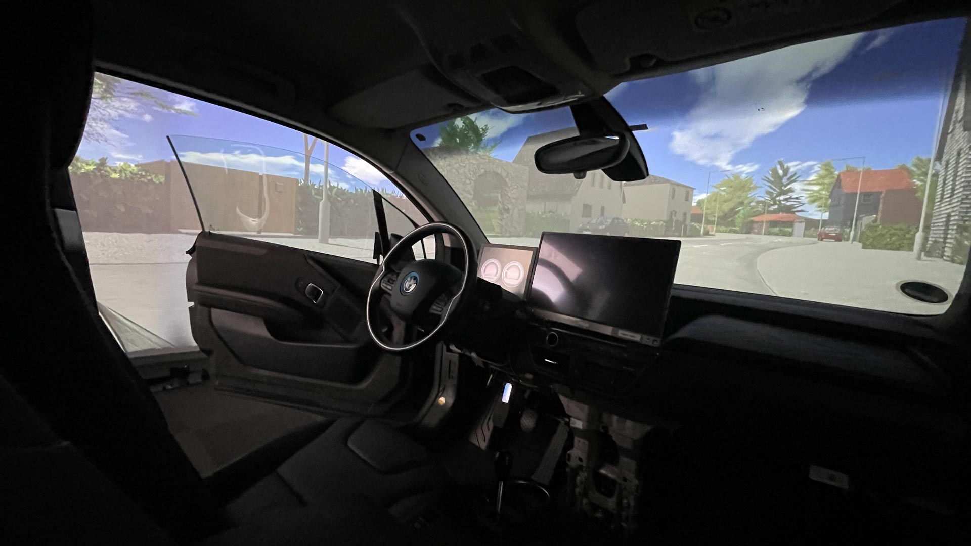 Intérieur d'une voiture avec portière, fenêtre du conducteur ouverte et tableau de bord numérique devant une vue sur la rue.
